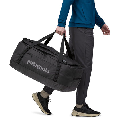 Hombre llevando del brazo la bolsa de viaje Patagonia Black Hole Duffel 70L en color negro